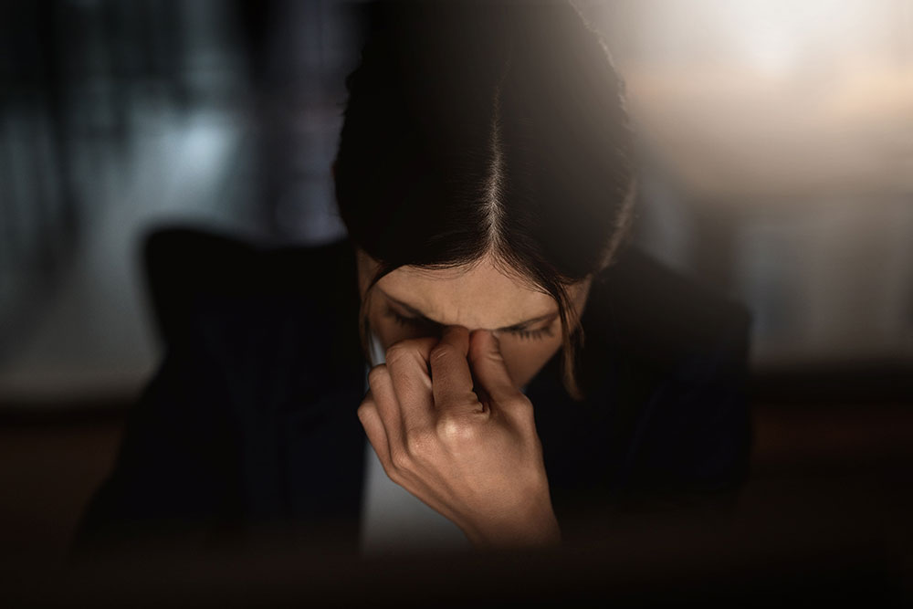 A girl holds her face at work from emotional burnout