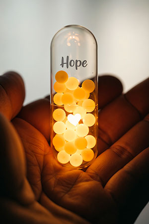 A man holds a glass container with glowing balls