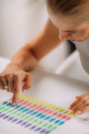 The girl puts paper clips on the table by color