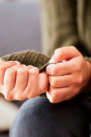 The man is nervous and fidgets with his sweater.