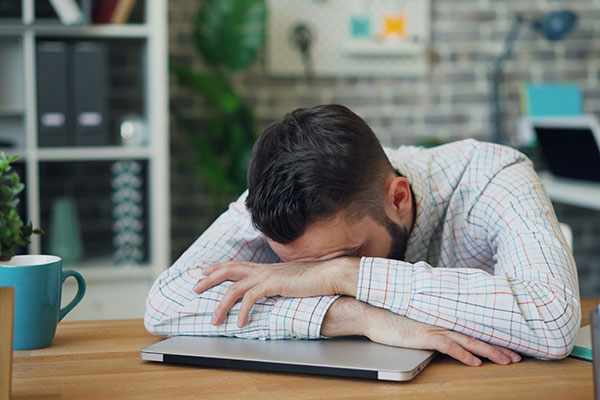 The tired man rested his head on his hands at the table